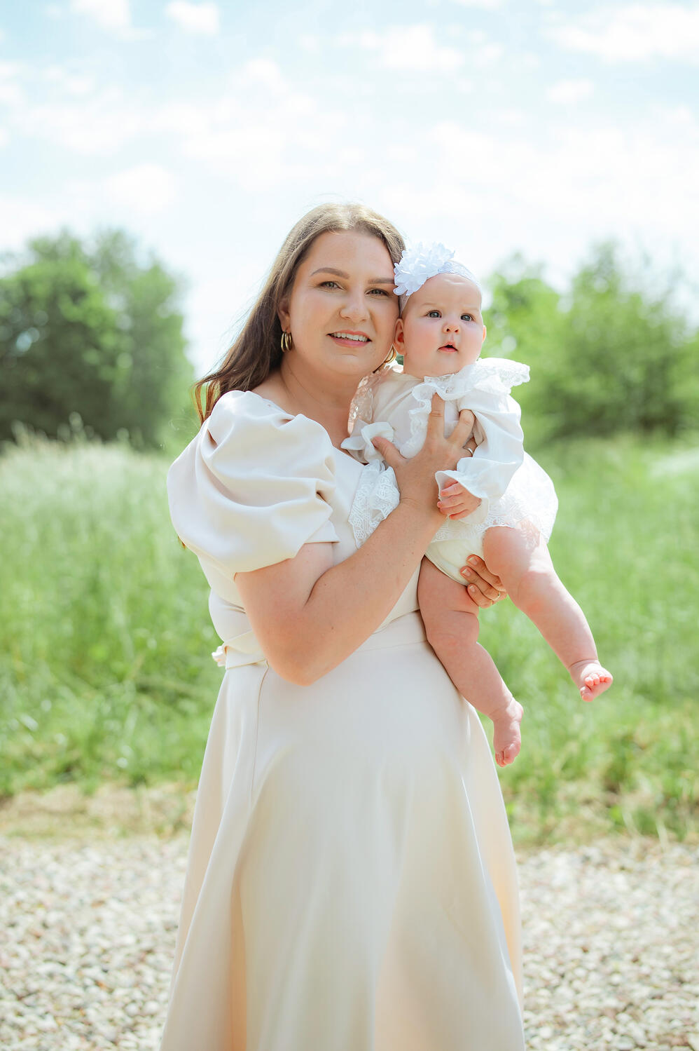 Mama apkabinusi dukrą pozuoja krikštynų fotografei