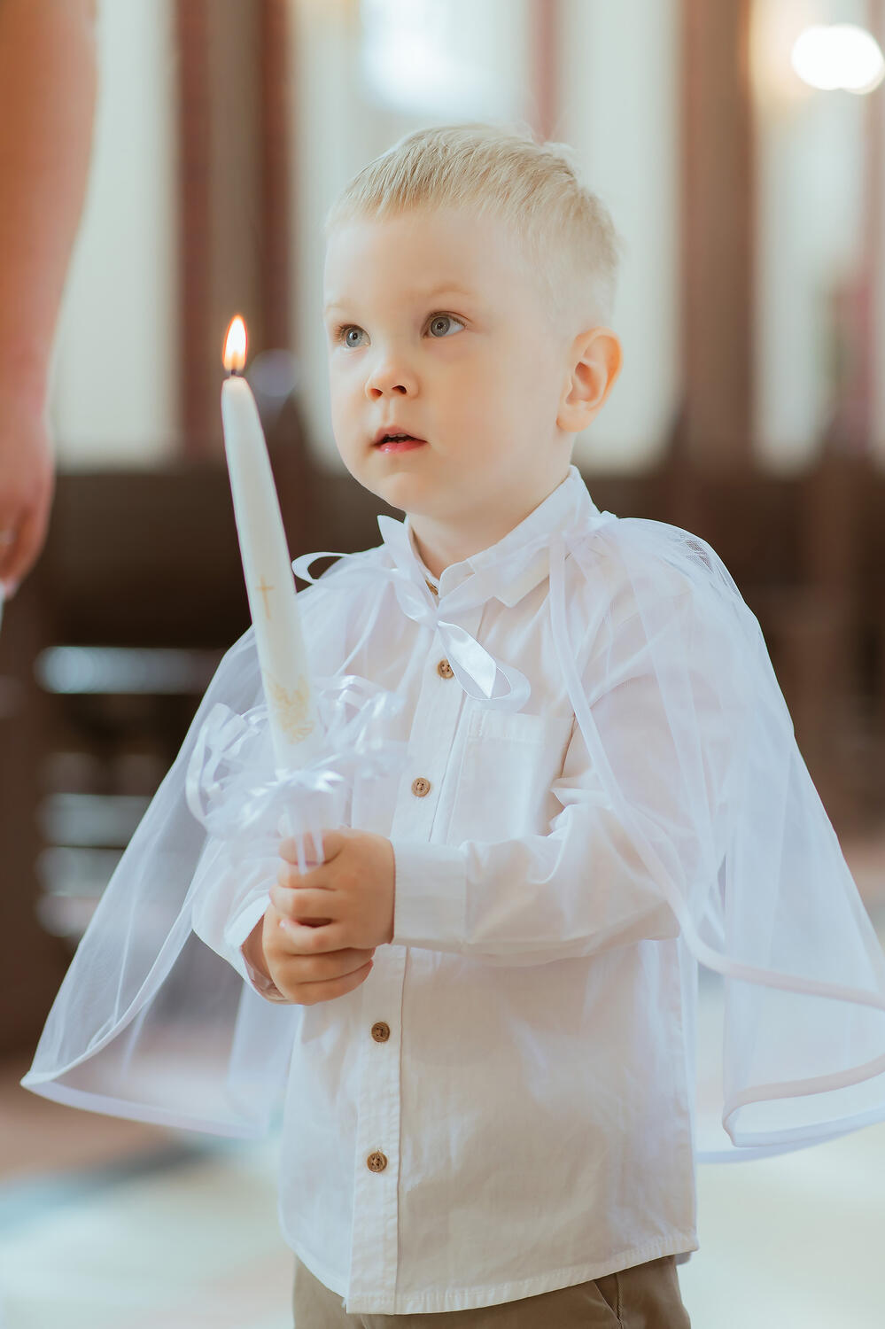 Krikšto sakramento fotografavimas , vaikas laiko žvakę
