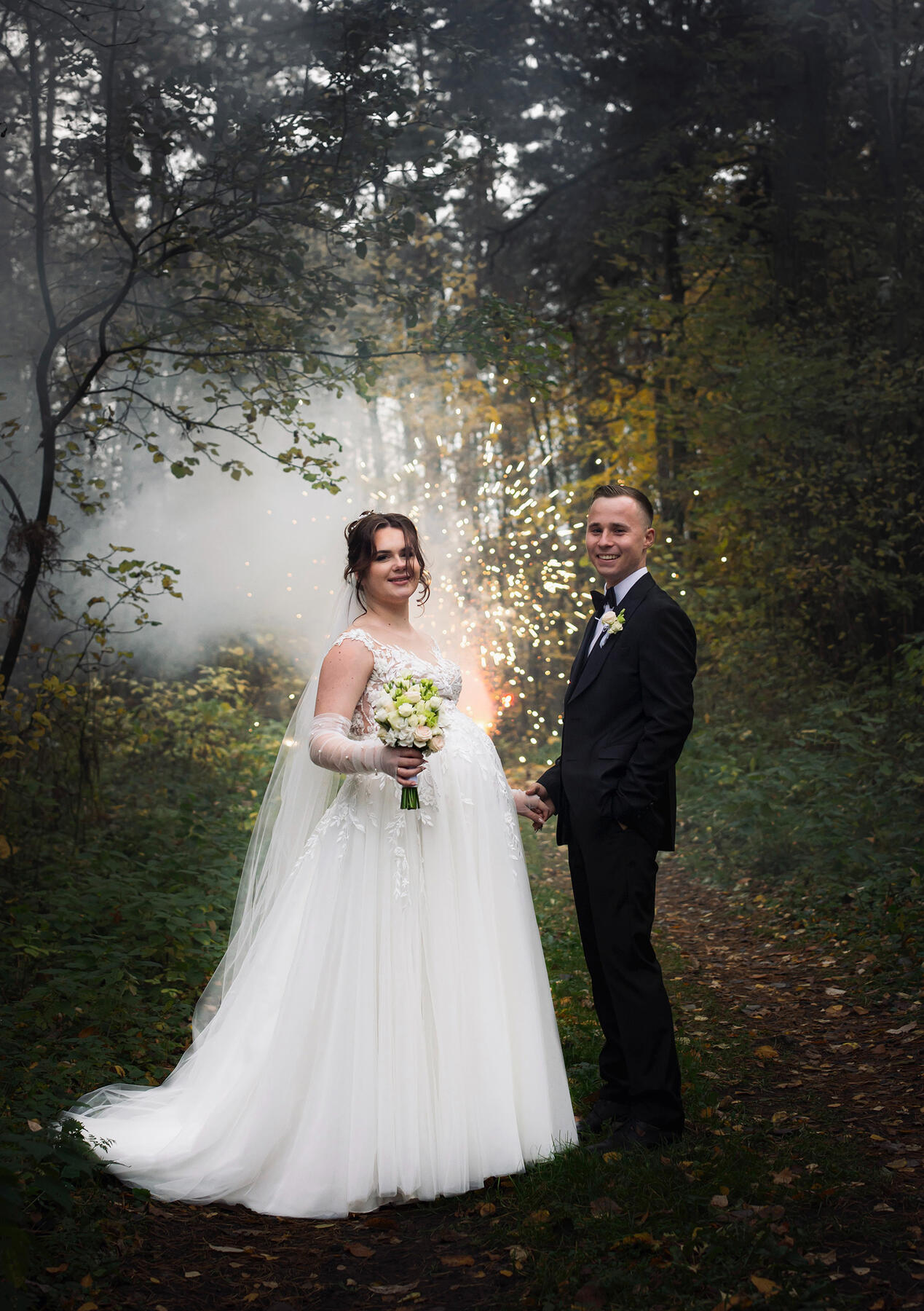 Jaunieji stovi prieš fejerverką, žvelgia į objektyvą