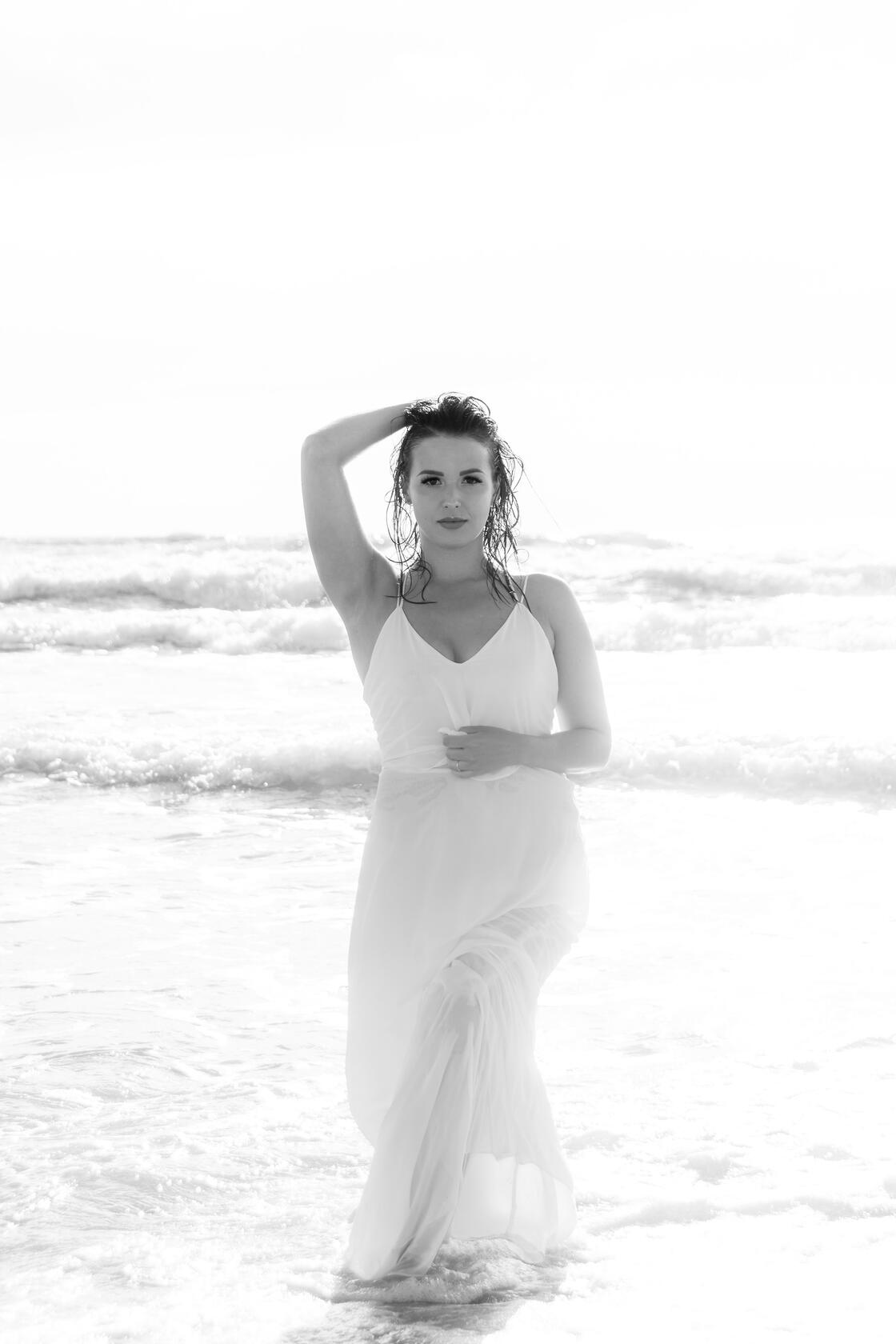 Mergina pajūryje pozuoja priešais bangas, asmeninė fotosesija.