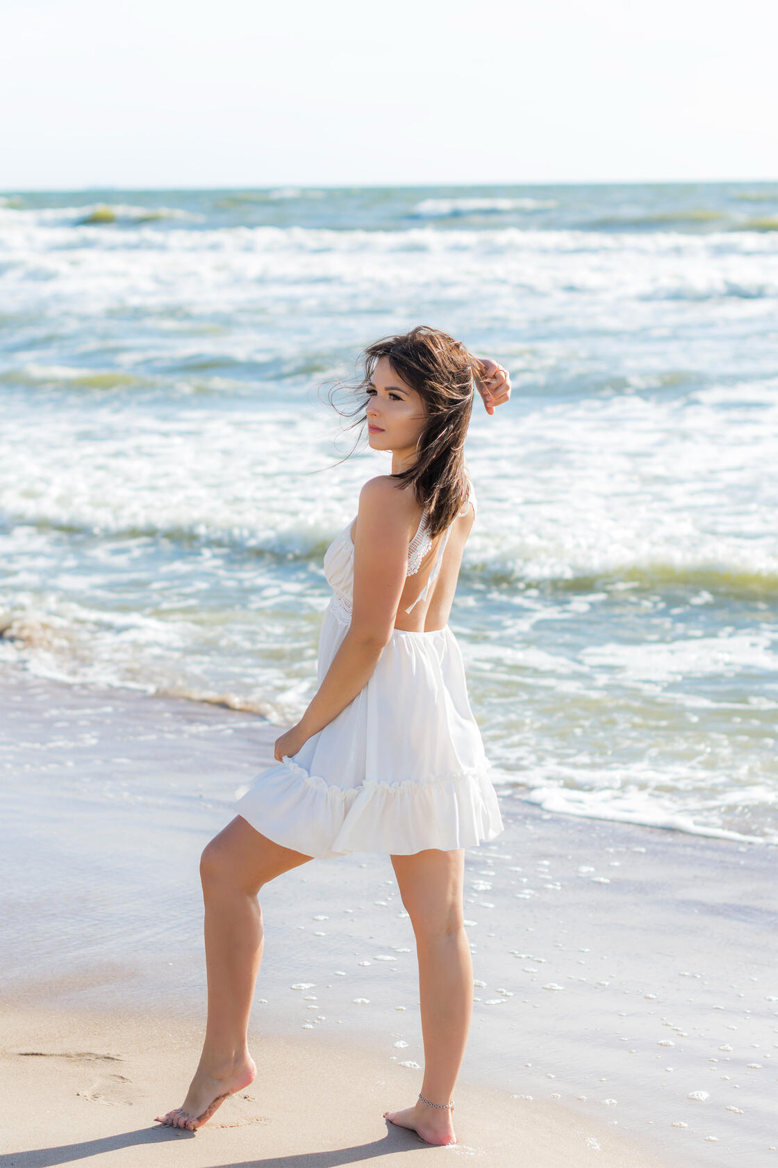 Mergina pajūryje pozuoja priešais bangas, asmeninė fotosesija.