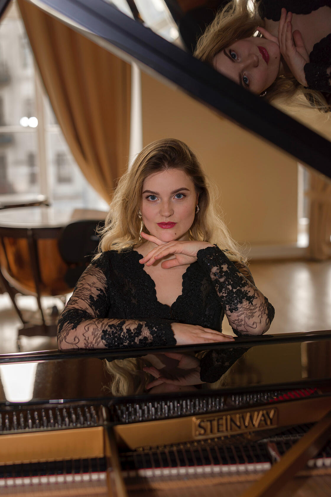 Pianistės portretas - muzikantė sėdi prie steinway fortepijono pasirėmusi ranka, žvilgsnis į objektyvą
