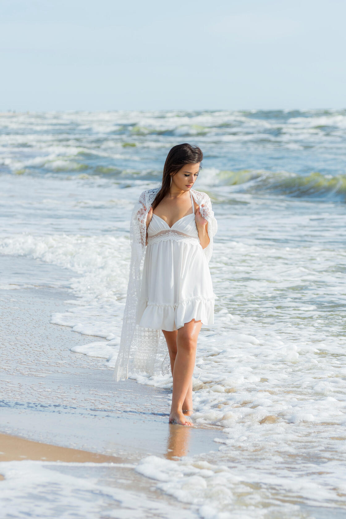 Susimąsčiusi moteris vaikšto bangų skalaujamu pajūriu - asmeninė fotosesija