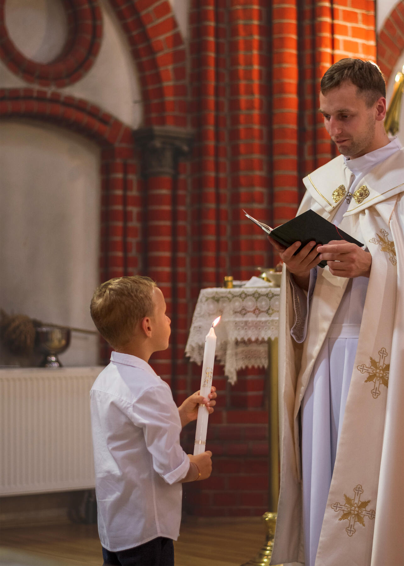 Krikšto ceremonija, kunigas skaito iš knygos, vaiko laiminimas