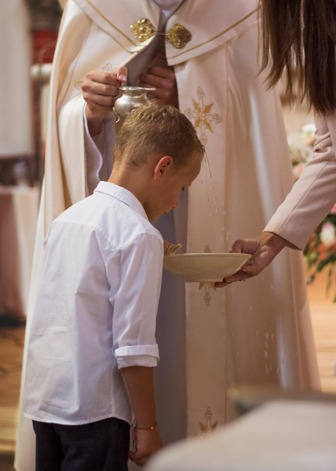 Krikštynų ceremonijas fotosesija, kunigas krikštija kitą berniuką, vanduo teko nuo jo galvos į indą