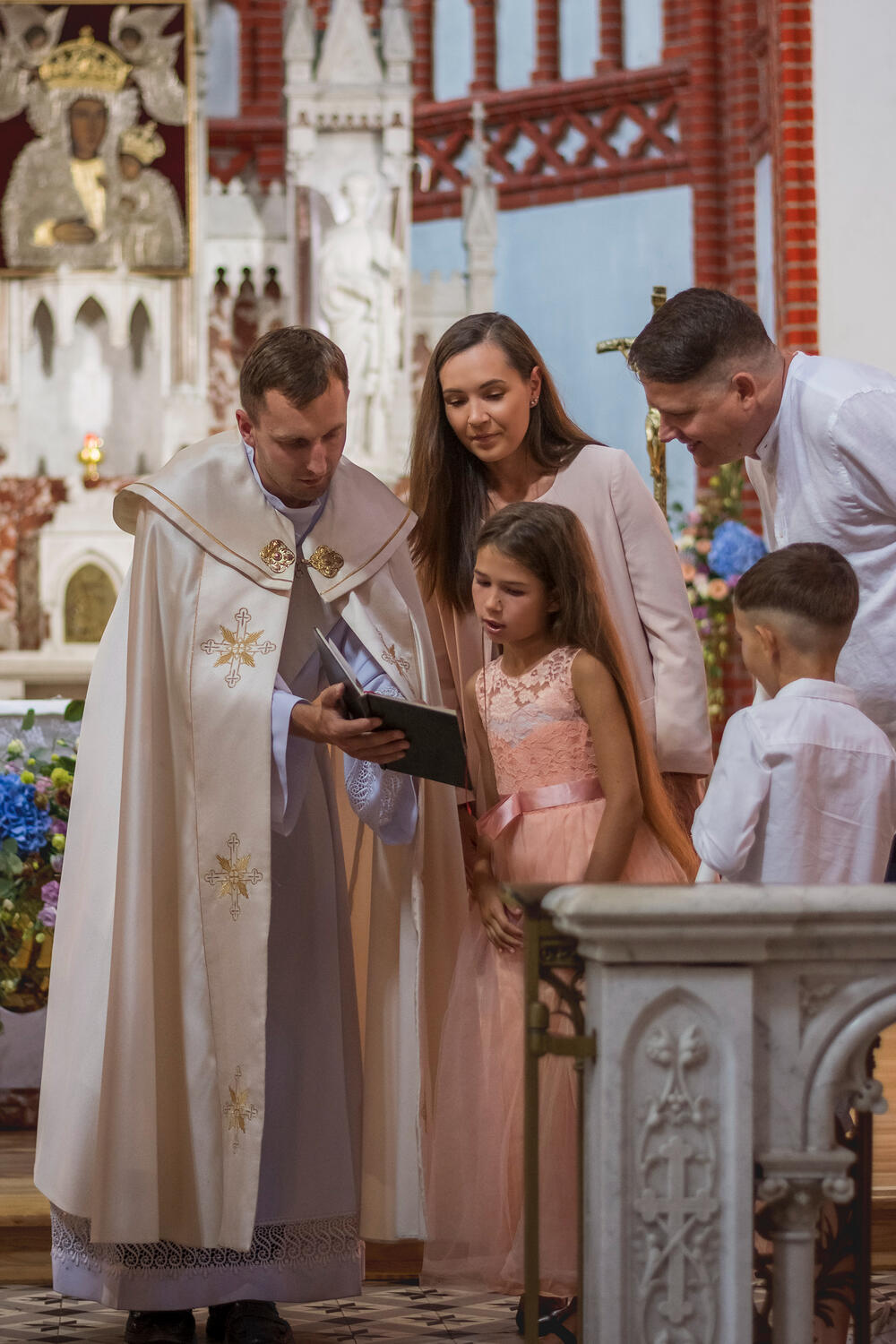 Kunigas, vaikai ir jų tėvai skaito iš šventos knygos