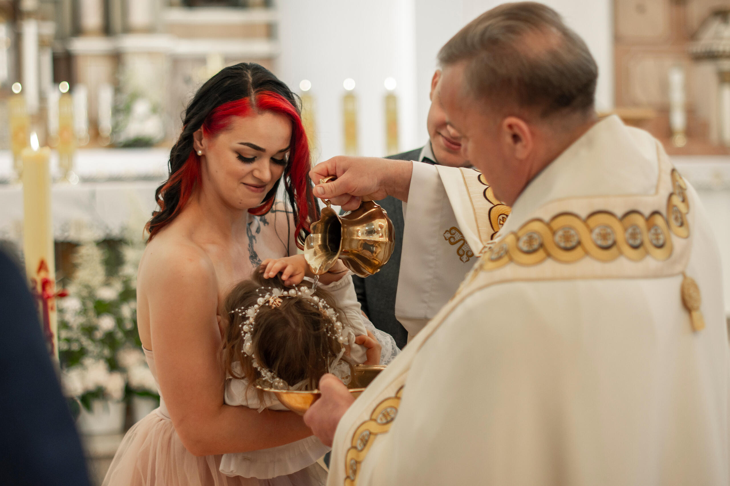 Untitled kunigas pila šventintą vandenį vaikui ant galvos