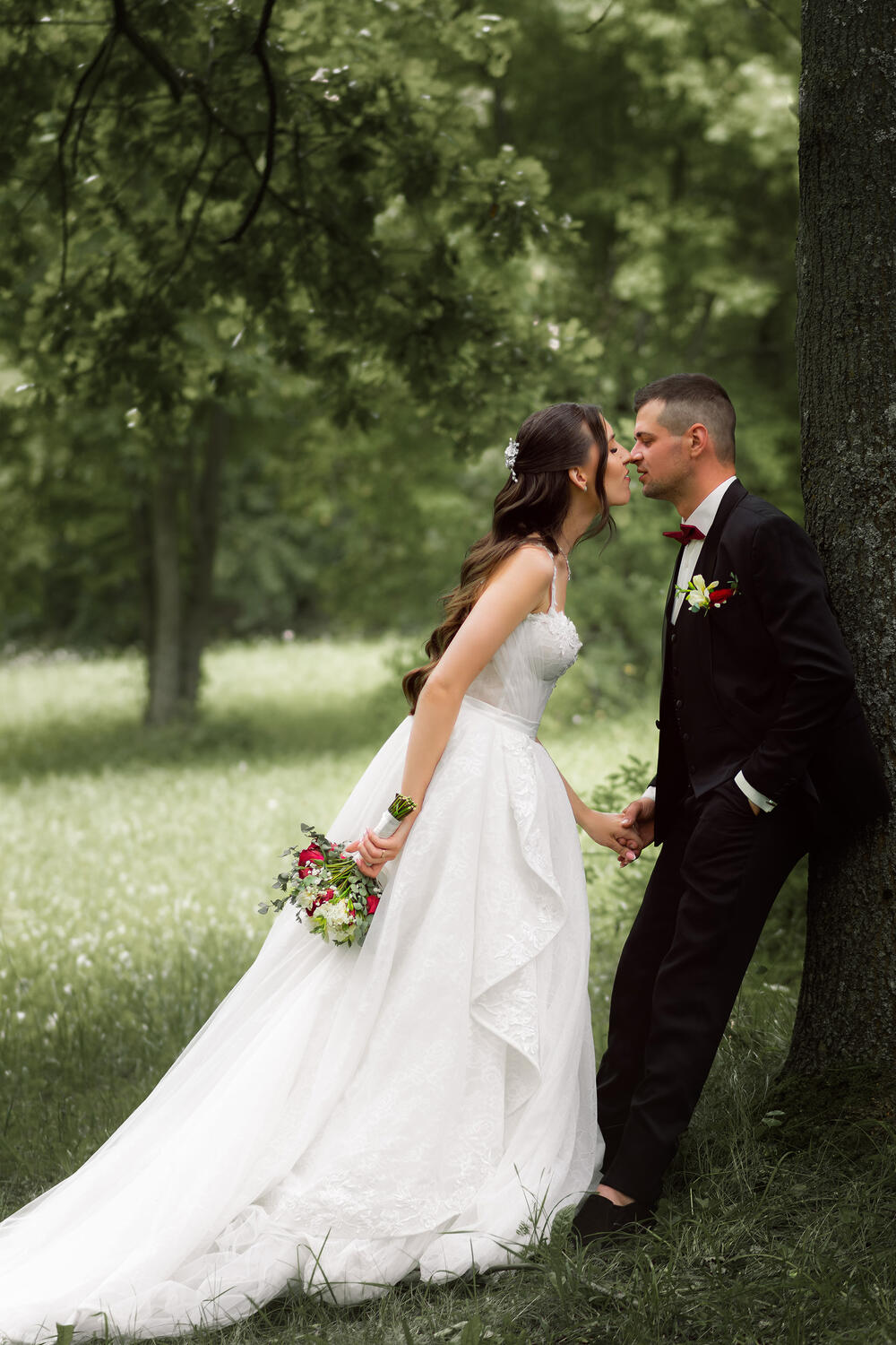 Jaunoji su balta suknele laiko vyro ranką ir siekia jį bučiuoti, vestuvinė fotosesija