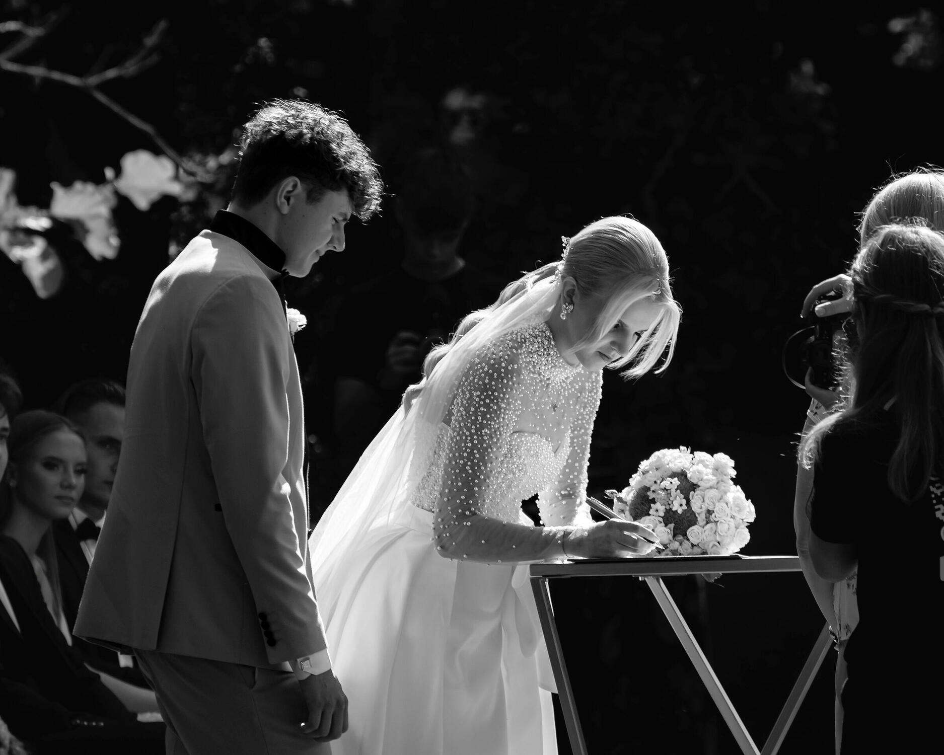 Vestuvių ceremonija, jaunoji deda parašą. Reportažinė fotografija