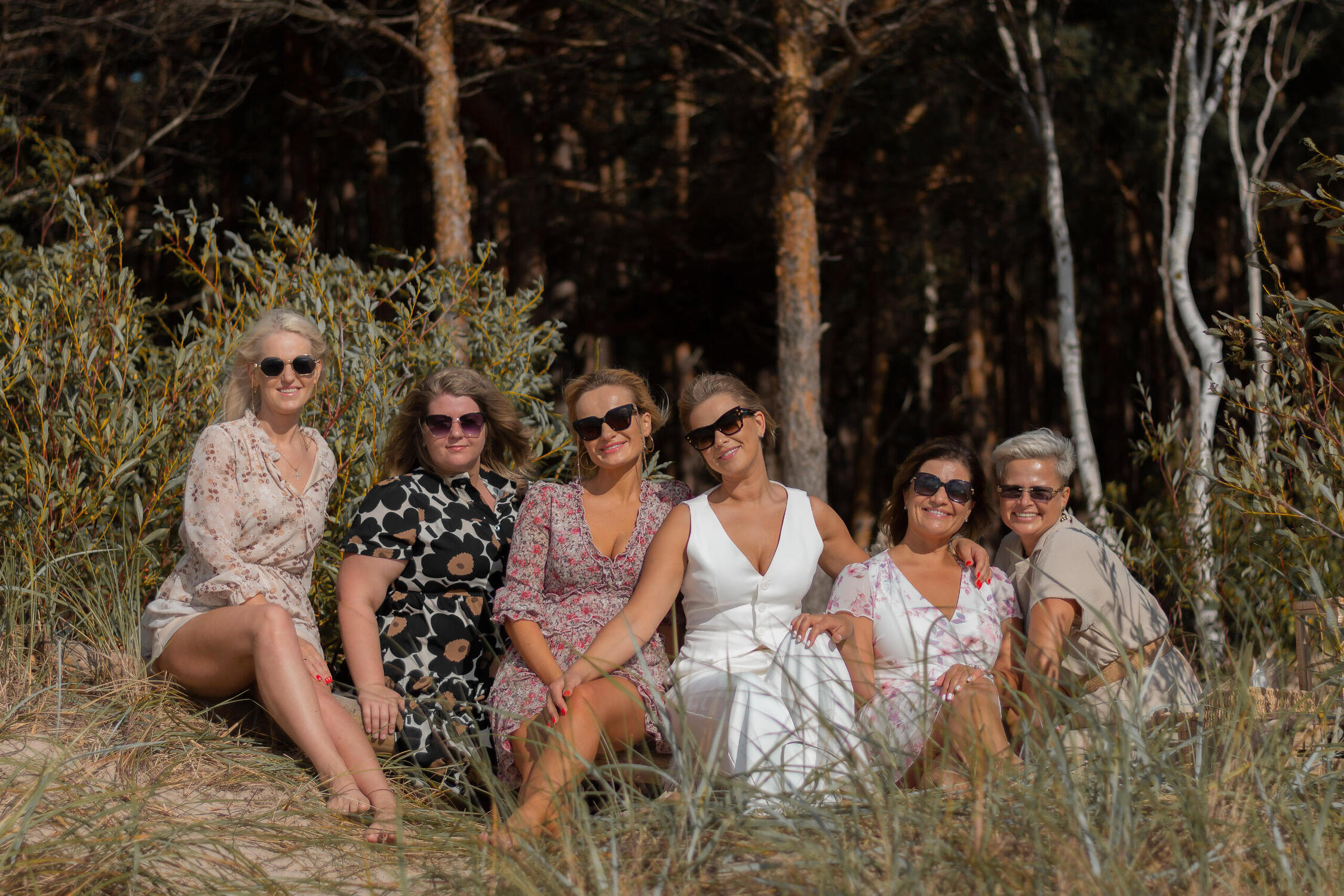 Moterys atsisėde ir susiglaude pozuoja fotografui