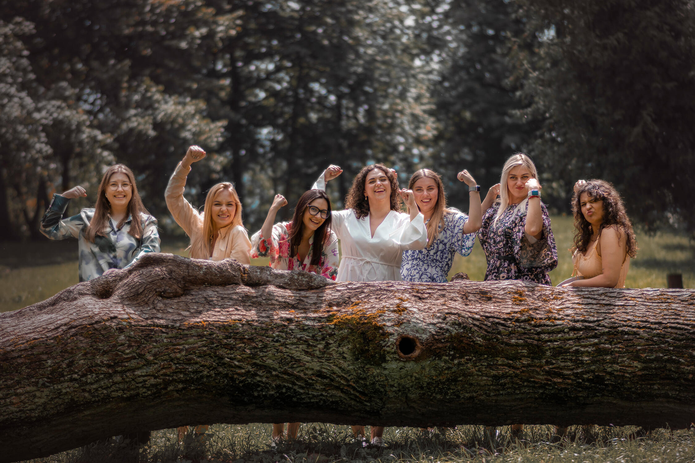 moterys pasirėmusios į medį pozuoja mergvakario fotografui