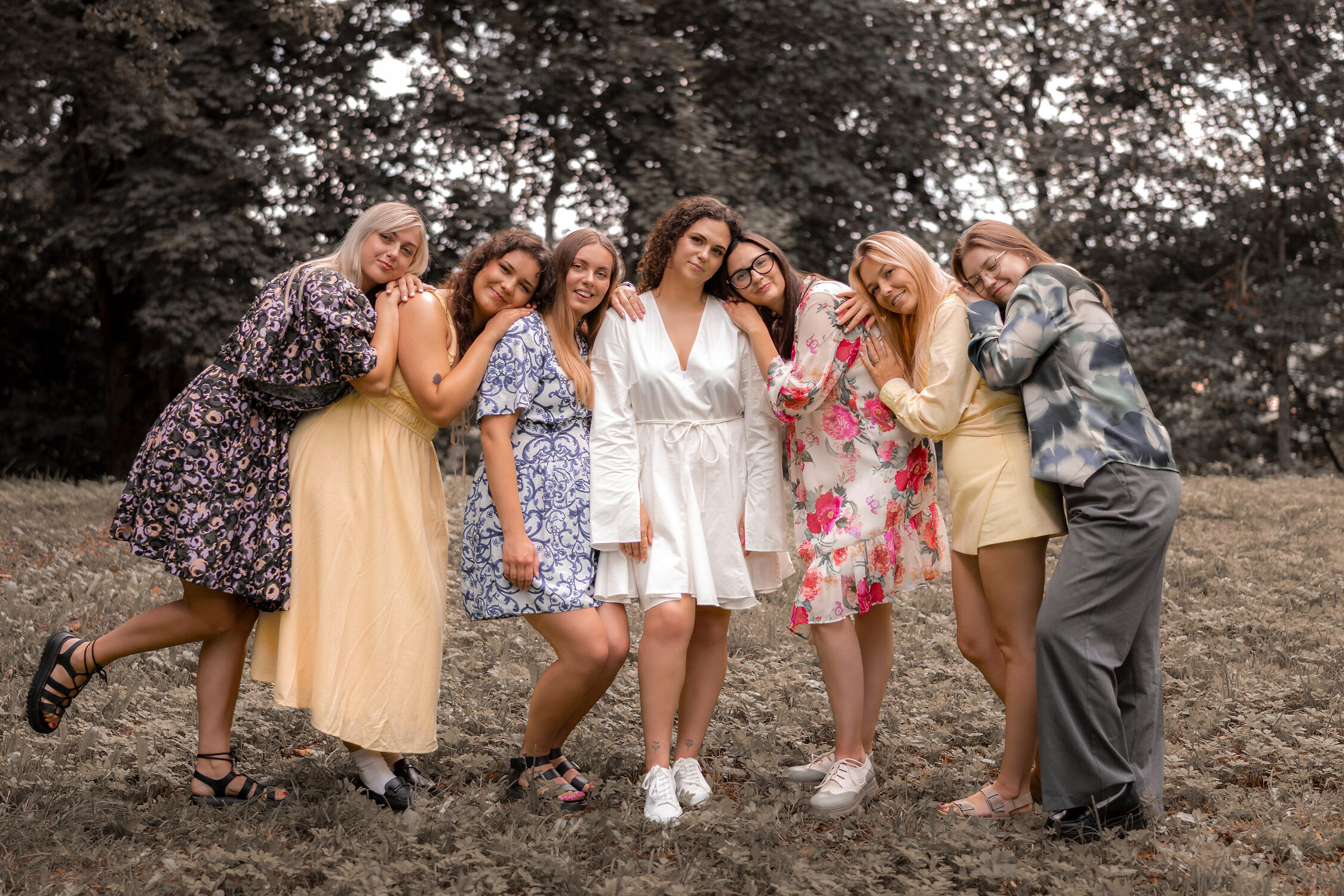 moterys pasipuošusios vasariškomis suknelėmis pozuoja prieš objektyvą, mergvakario fotosesija