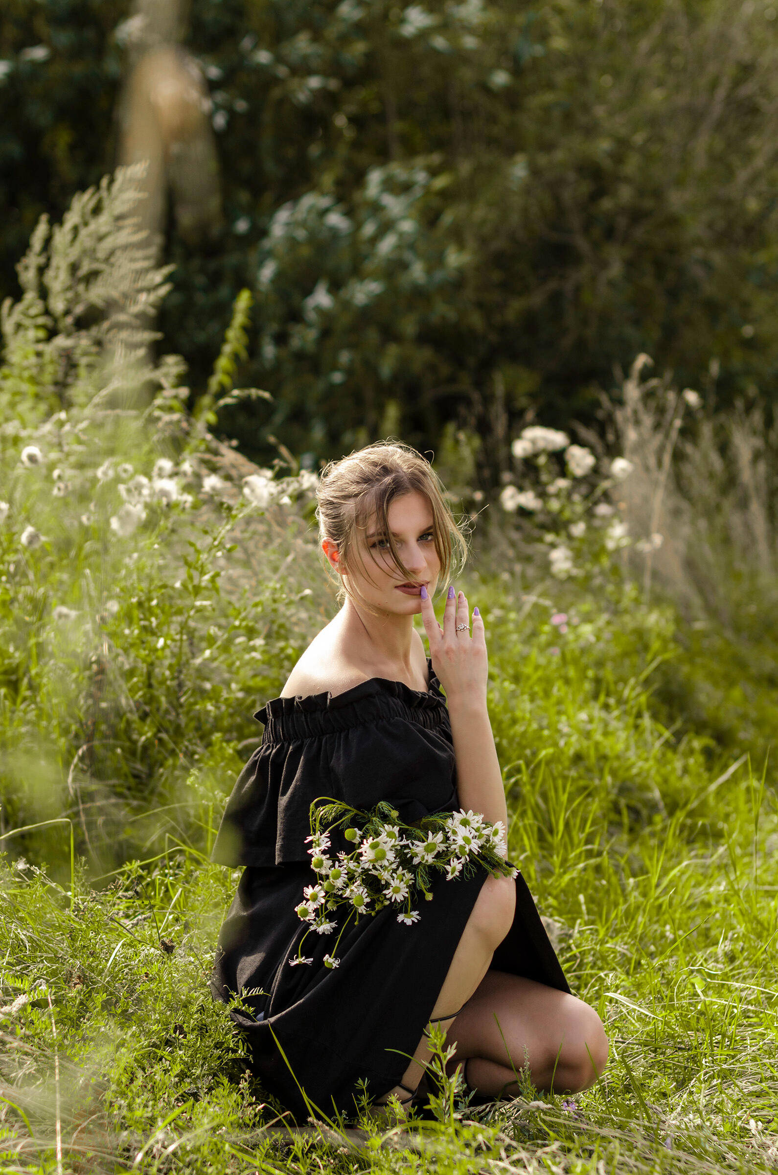 Mergina pozuoja su lauko gėlėmis, bendras planas