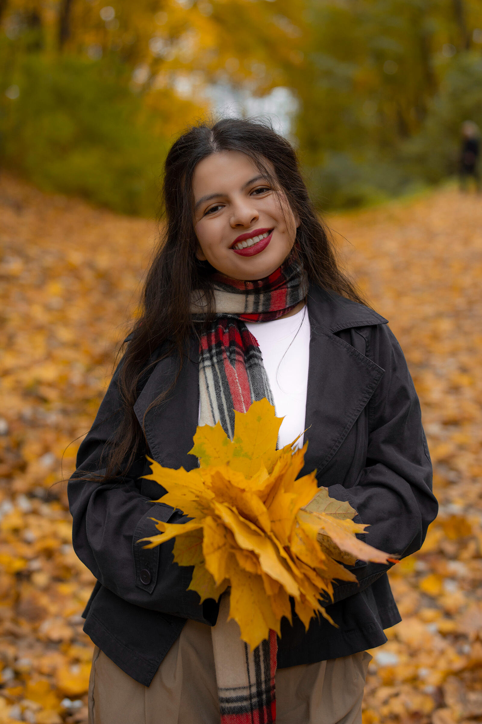 Mergina pozuoja su rudeniniais lapais, portretas